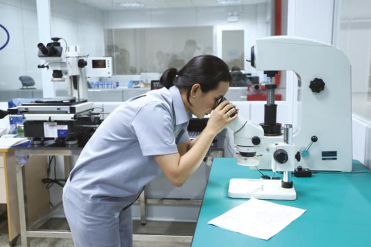Engineer inspecting a sample under the OLYMPUS microscope